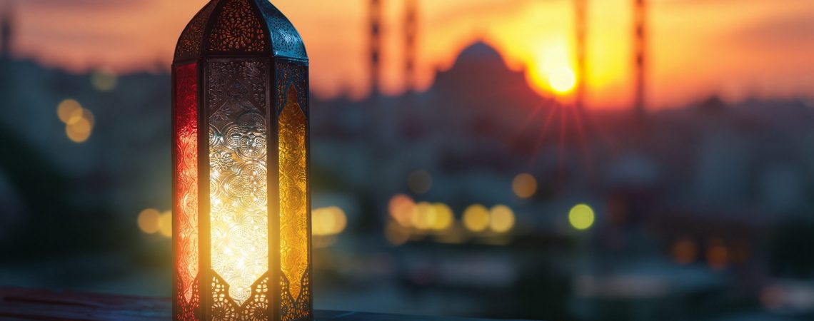Ornamental Arabic lantern with burning candle glowing at night mosque background. Festive greeting card, invitation for Muslim holy month Ramadan Kareem.
