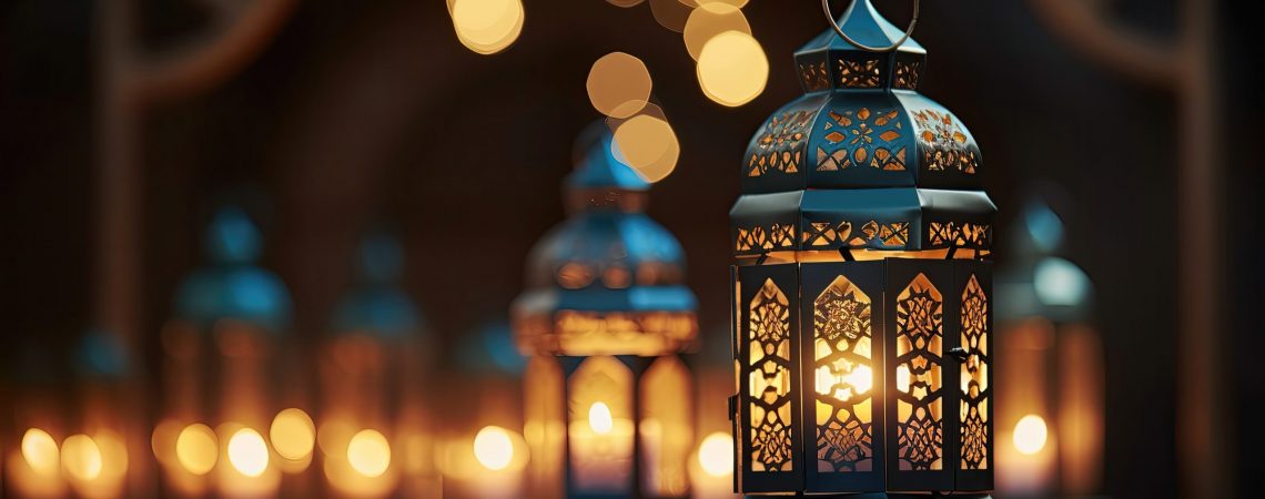 A decorative lantern with a burning candle glowing against the backdrop of a night mosque.